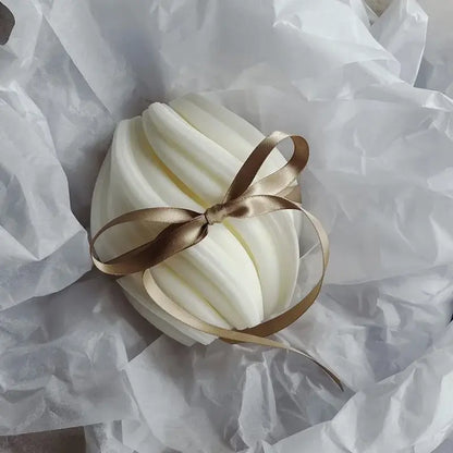 Bougie parfumée en tourbillon blanche avec un ruban, fabriquée à 100% en cire de soja, présentée sur du papier de soie.