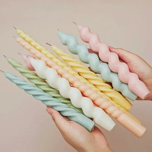 Bougies d'aromathérapie en cire d'abeille en forme de bâton spirale multicolores tenues par une personne